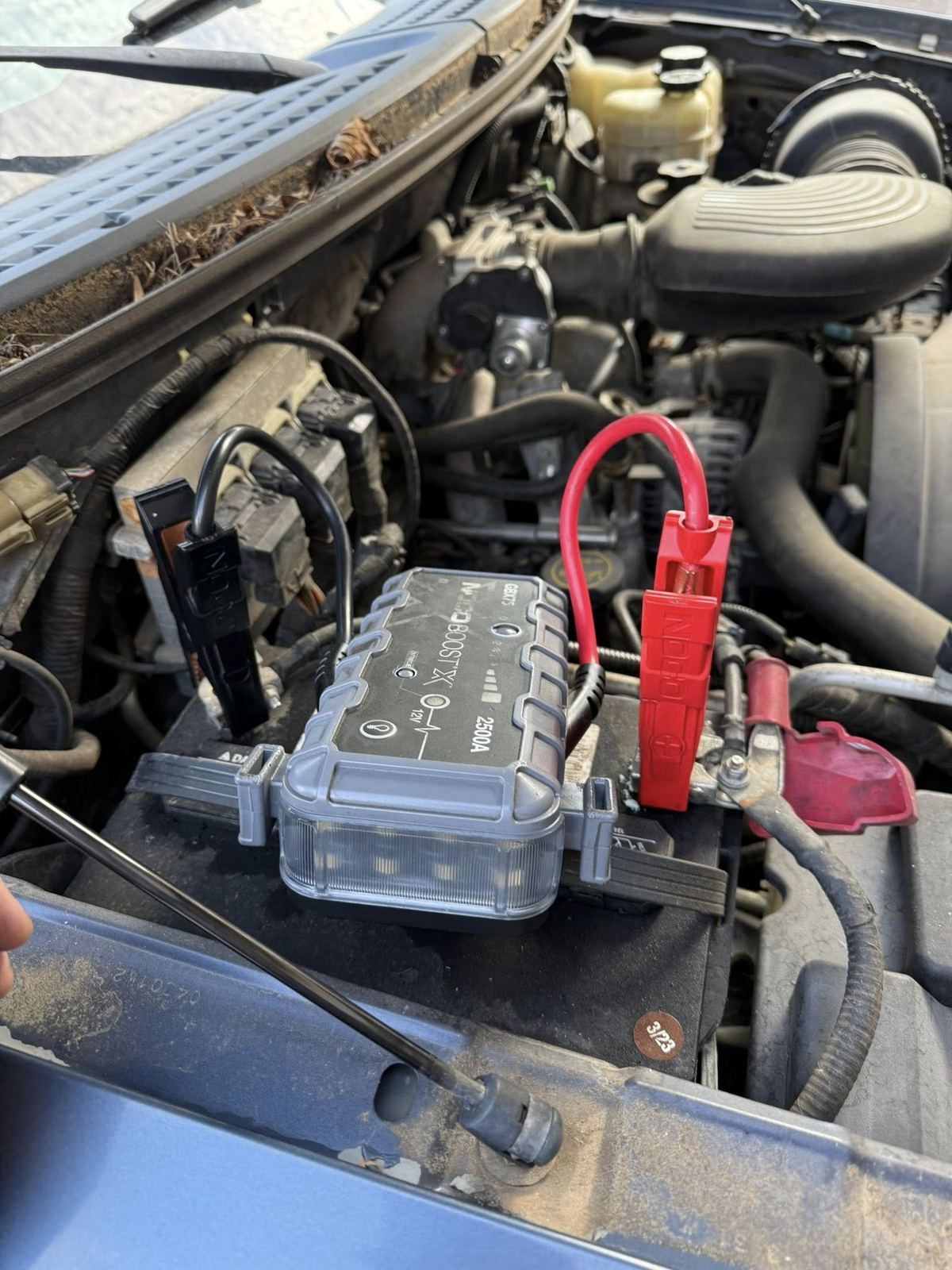 Professional jump starter clamped to a customer's car battery