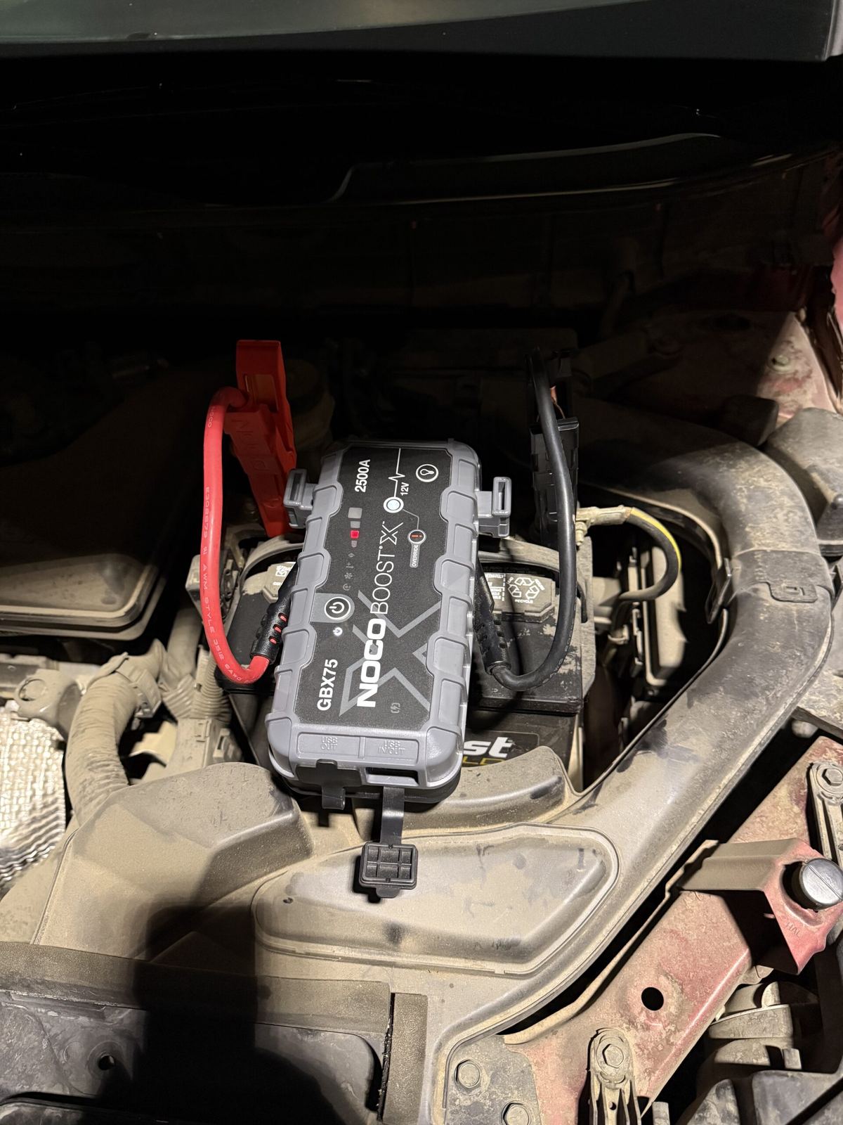 Jump starter connected to a car battery under the hood