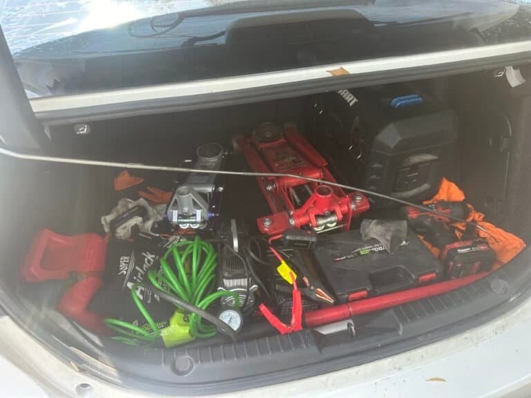 Open car trunk showing emergency tools and equipment inside.